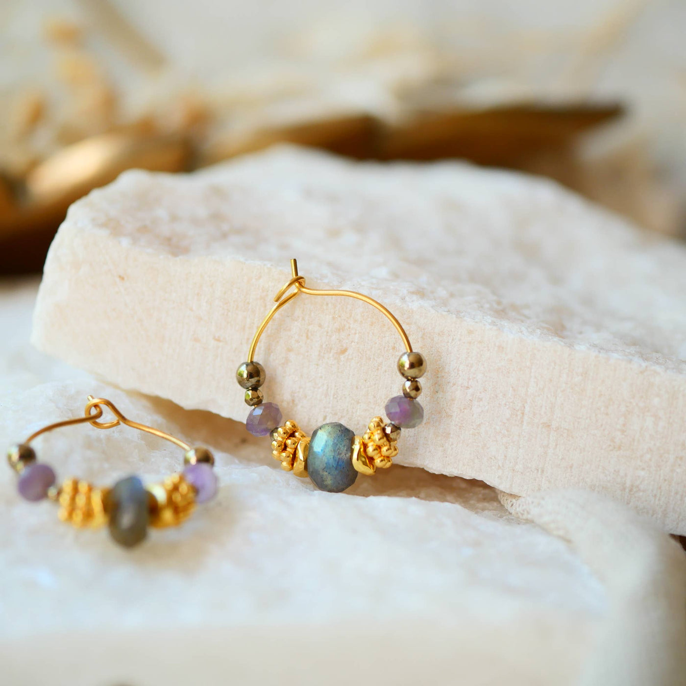 Zwei goldene Creolen-Ohrringe mit Labradorit-Perlen und kleinen violetten Akzenten.
