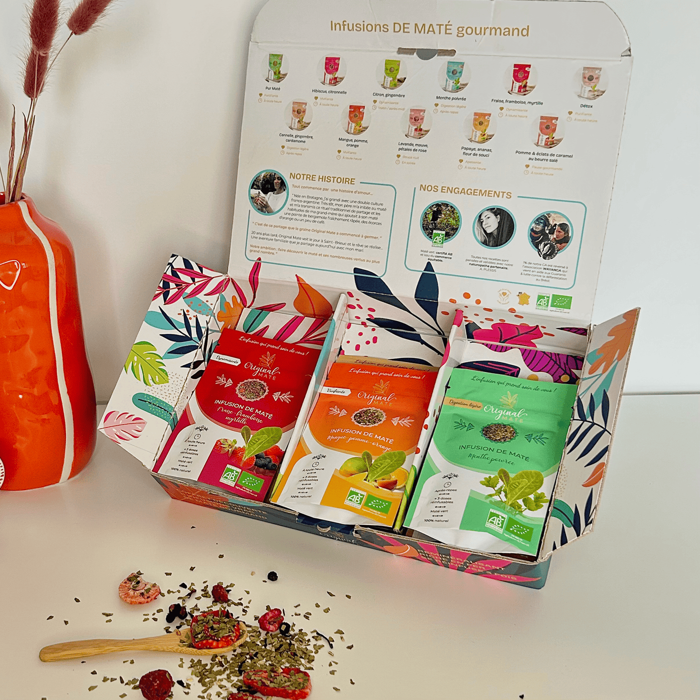 Bunte Mate-Beutel mit Kräuterdekoration, natürliche Produktpräsentation.