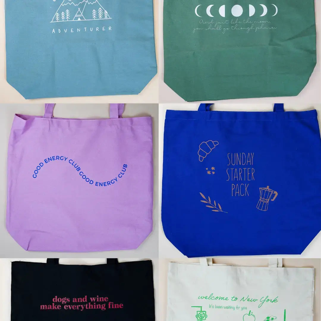Bunte Hellblaue Baumwolltasche mit Mondphasen-Print und dem Spruch „And just like the moon, you shall go through phases“, getragen über der Schulter.